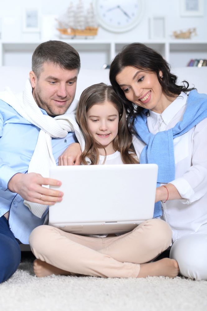 Portrait,Of,Parents,And,Daughter,Using,Laptop,In,Room